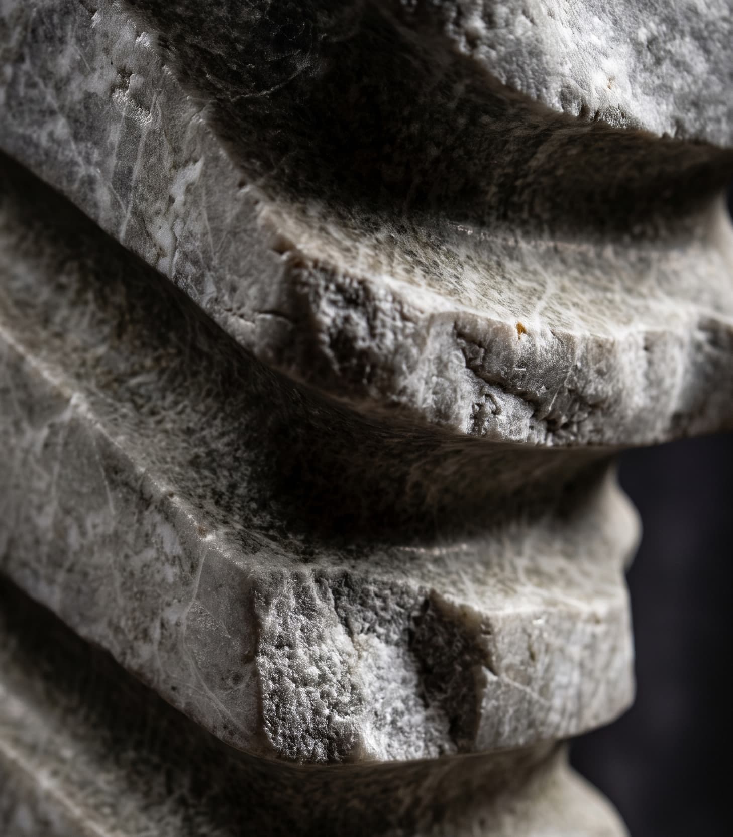 Detail of a carved stone sculpture, stacked angular planes catching raking light